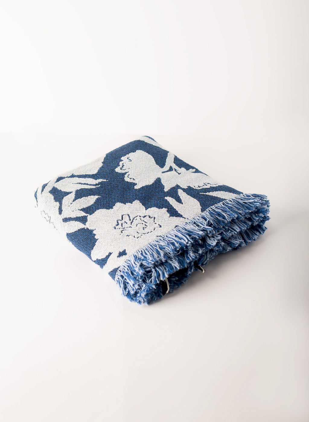 Folded blue and light blue floral blanket from the angled sideview on a light background