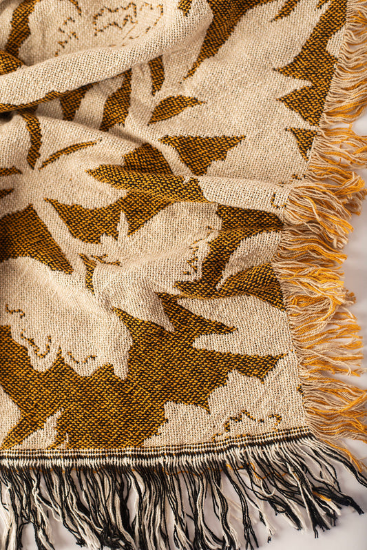 Close-up of Addy Ochre gold and cream floral woven cotton throw with fringe