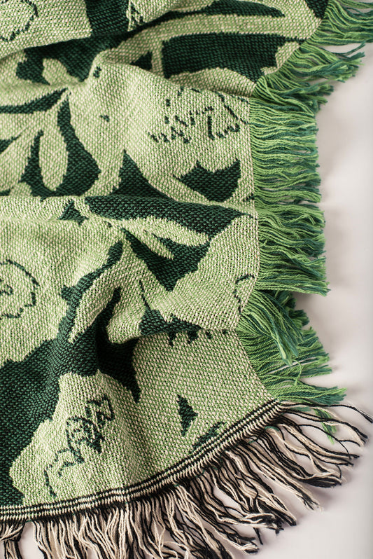 Close-up of Addy Spruce dark and light green floral woven cotton throw with green fringe