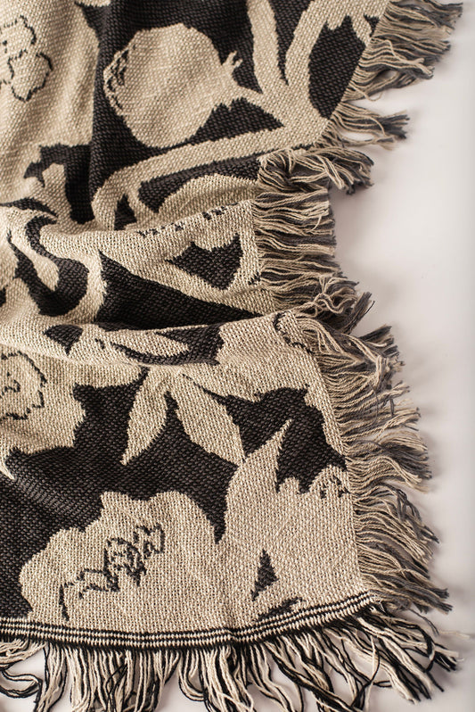 Close-up of Addy Tuffet charcoal, taupe, and cream floral woven cotton throw with fringe