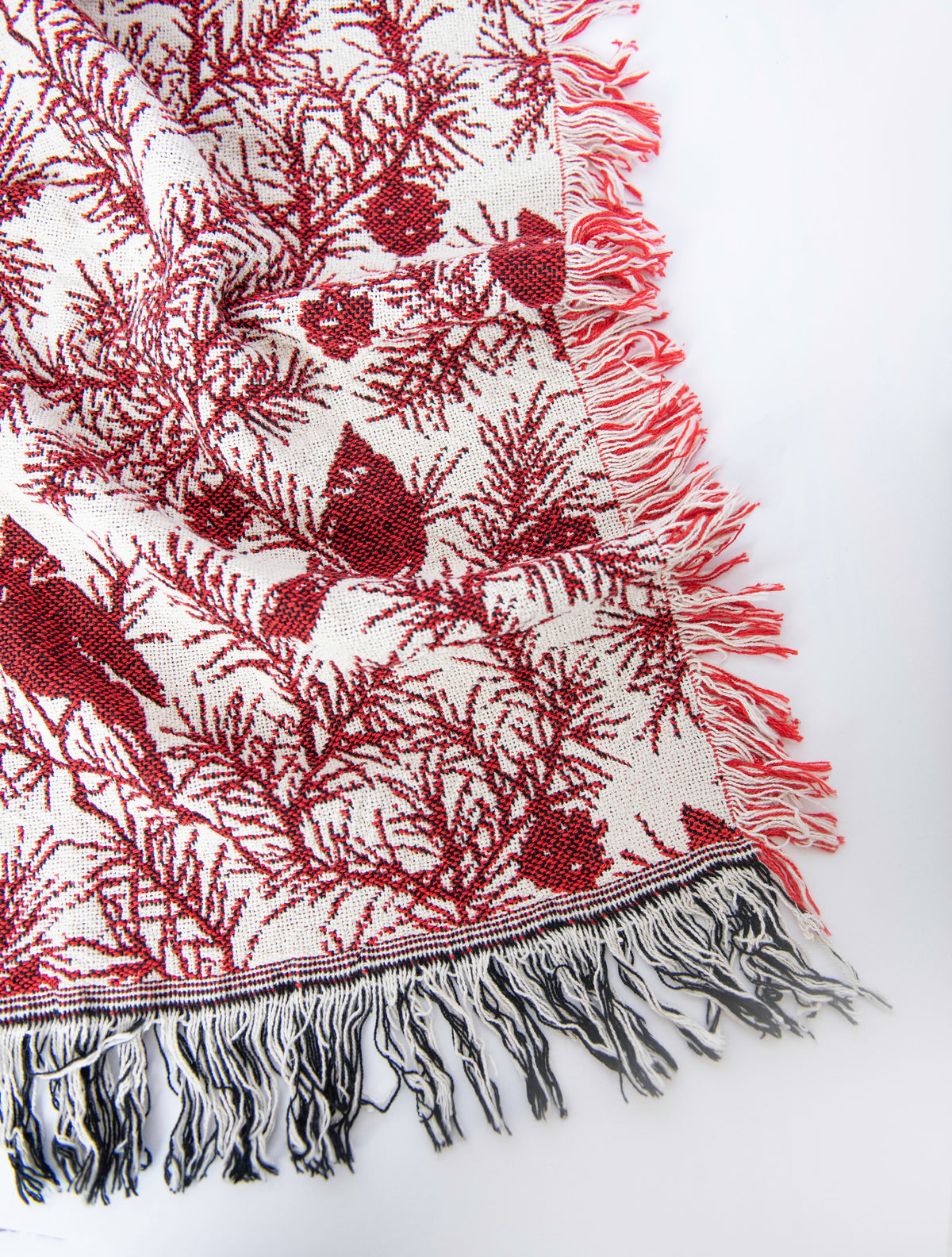 Close-up of Cherie Cranberry red cardinal, pine branch, and pinecone woven cotton throw with fringe
