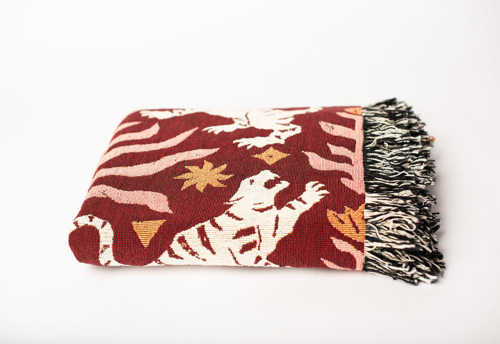 Front view of folded red and cream tiger folk-art woven throw blanket with fringe