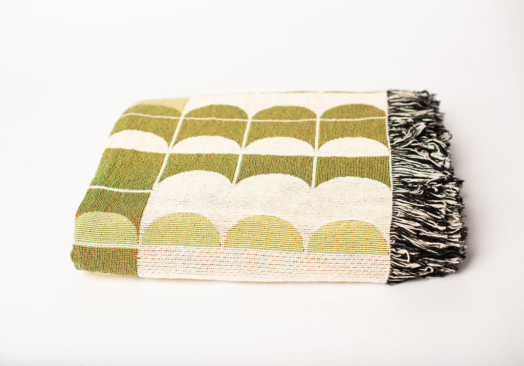 Front view of folded green and cream scallop-patterned woven throw blanket with fringe