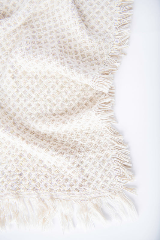 Close-up of Rowan cream and beige diamond-patterned woven cotton throw with neutral fringe