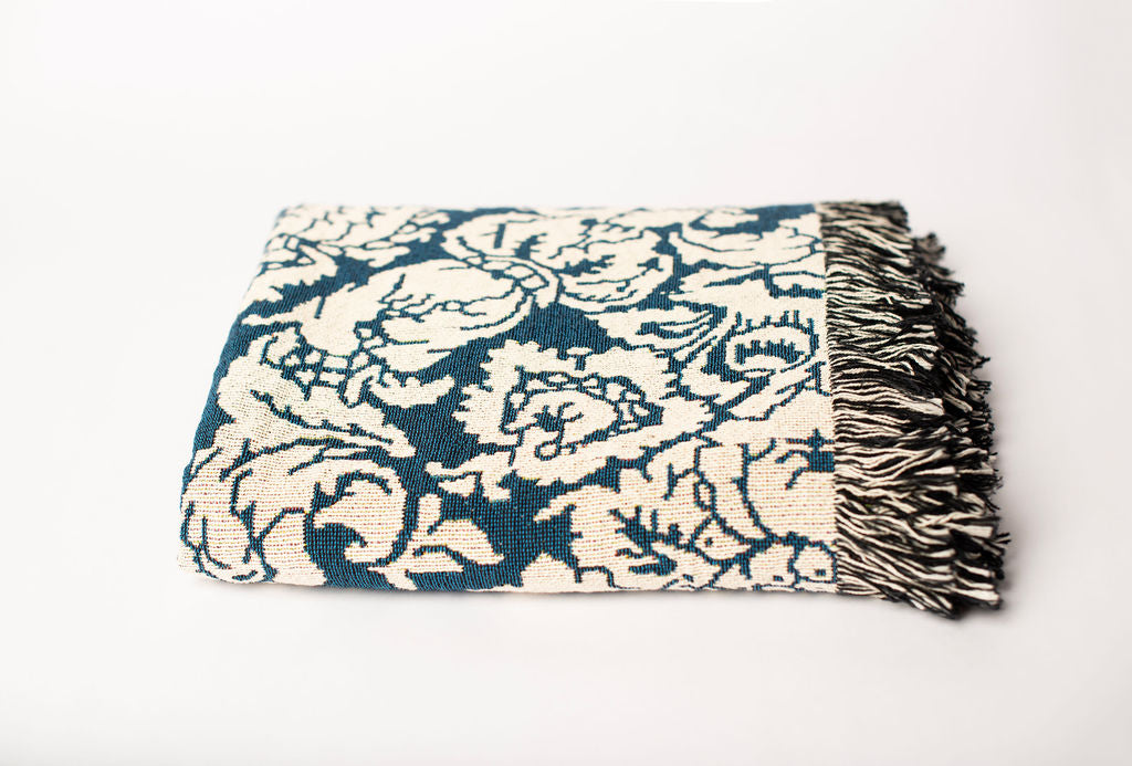 Front view of folded blue and cream damask floral woven throw blanket with fringe