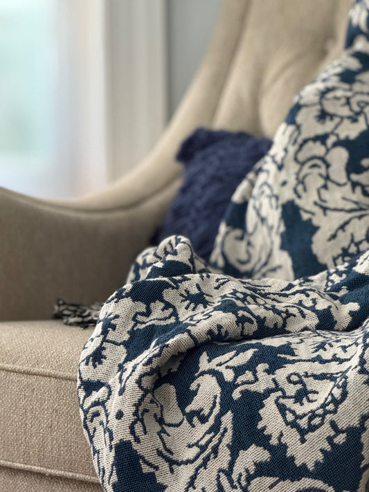 Verona Cerulean blue damask floral throw blanket draped over an upholstered sofa beside a navy pillow